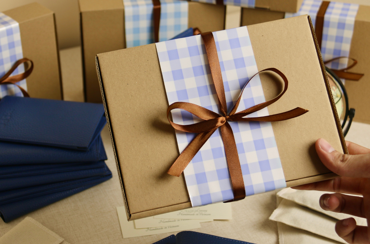 Hand holding a kraft gift box tied with ribbon
