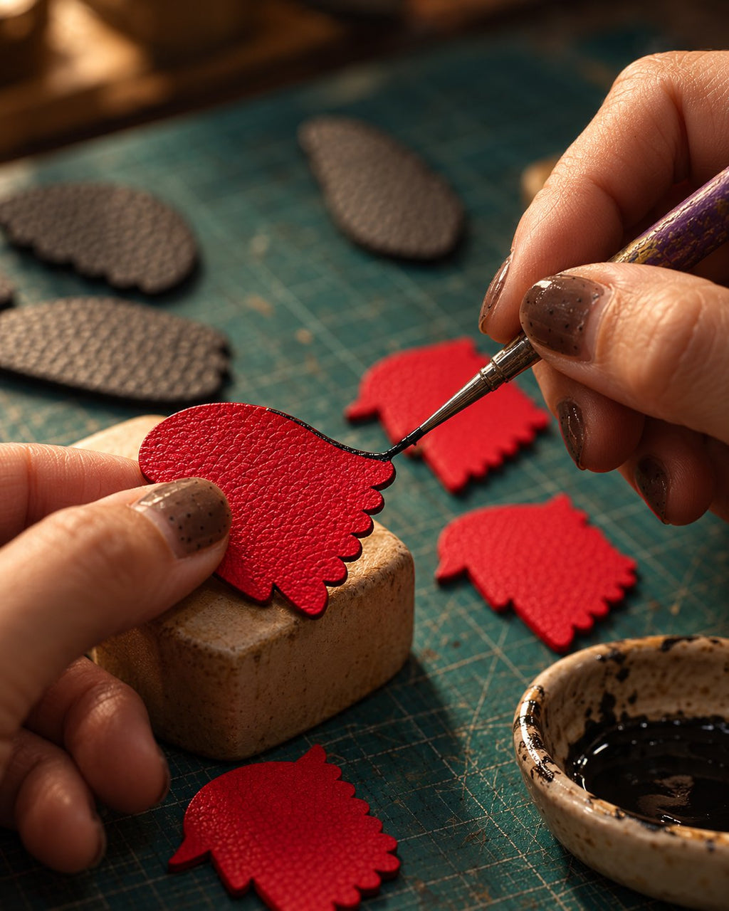 Artisan hand-painting the edge of a leather piece